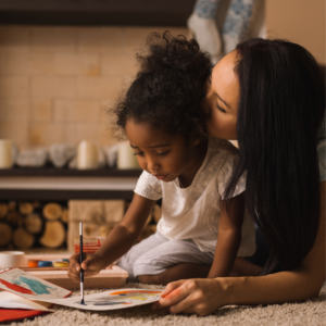 Mother and young daughter painting on the floor