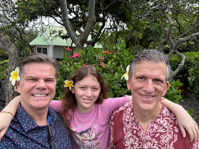 gay couple with daughter posing with flowers in hair
