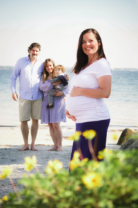 Pregnant surrogate poses with expecting family