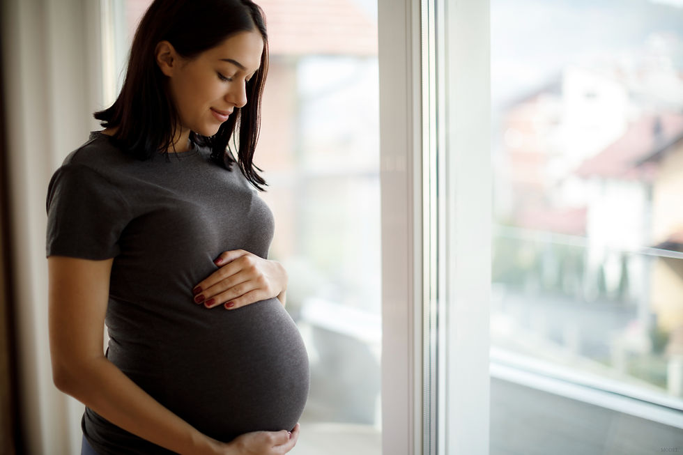 Pregnant woman gently cradling her belly with a serene expression (model)