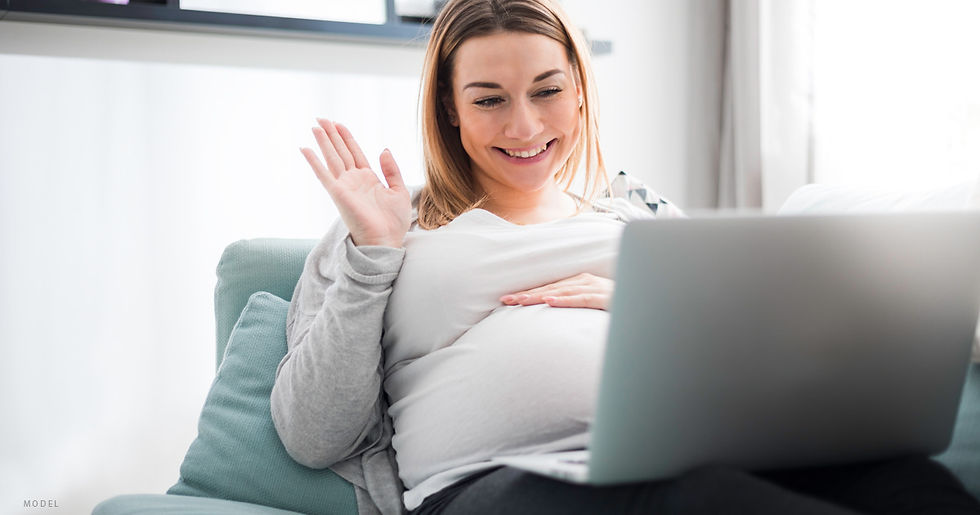 Pregnant woman waving at a computer screen