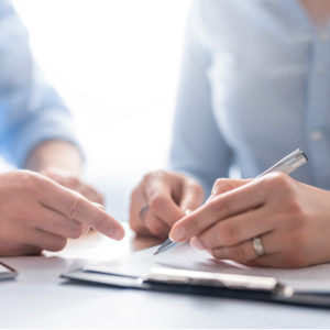 Close-up on hands signing paperwork