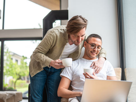 Same-sex male couple reviewing surrogacy costs on a computer. Source: Getty Images. Credit: AzmanL