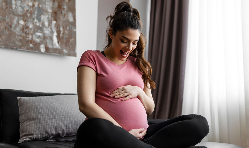 Pregnant woman gently cradling her belly with a happy expression (model)