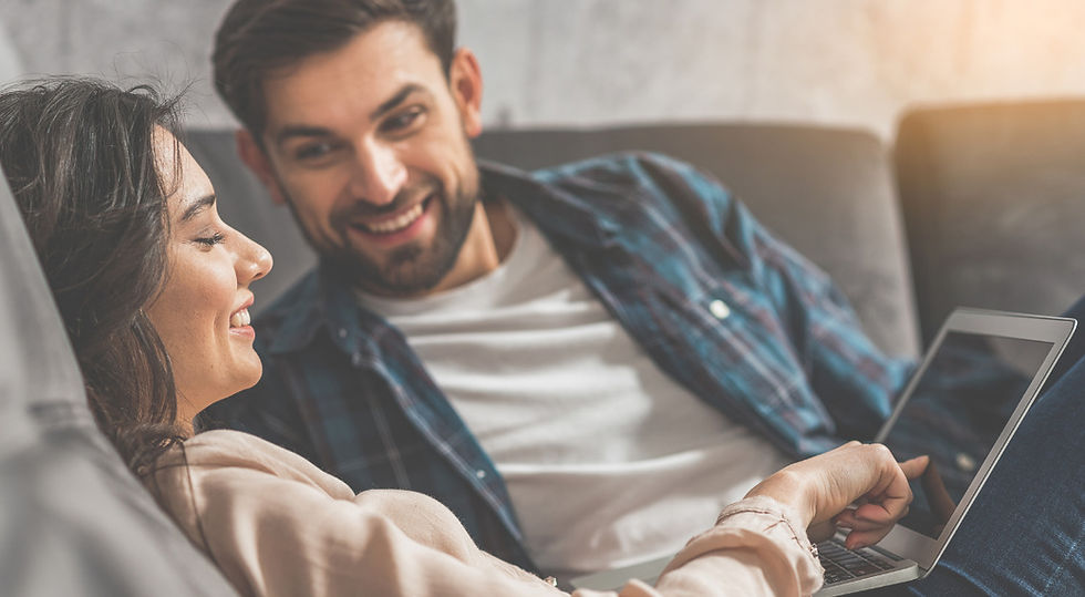 couple smiling while looking at laptop