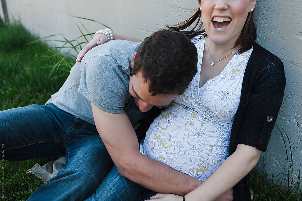 A man hugs a smiling pregnant woman.