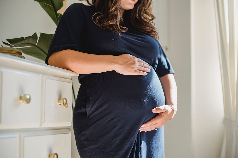 Pregnant woman in hospital gown laughs with friend.