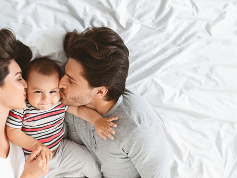 Intimate family portrait of two parents sharing a tender moment with their baby through surrogacy.