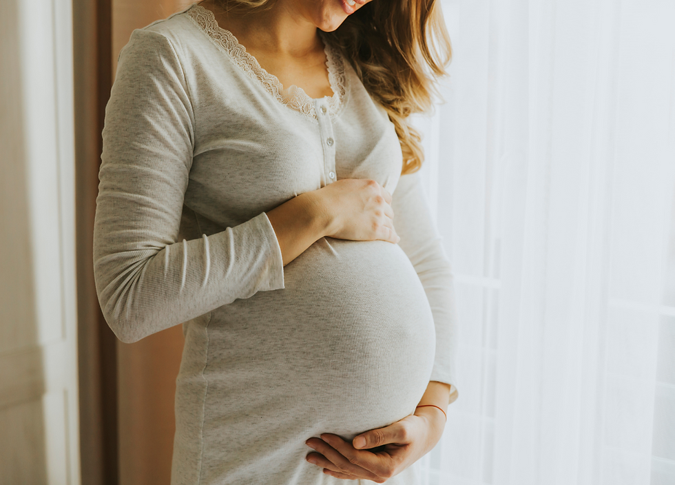 A smiling woman holds her pregnant belly, embodying the joy and fulfillment of meeting surrogate requirements.